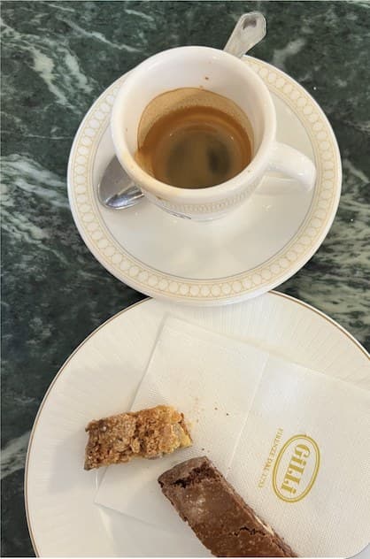 An espresso and two small pastries on a marble table.
