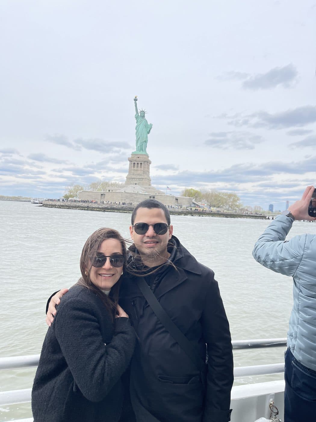 Adriana and Yair on a boat with the Statue of Liberty behind them.
